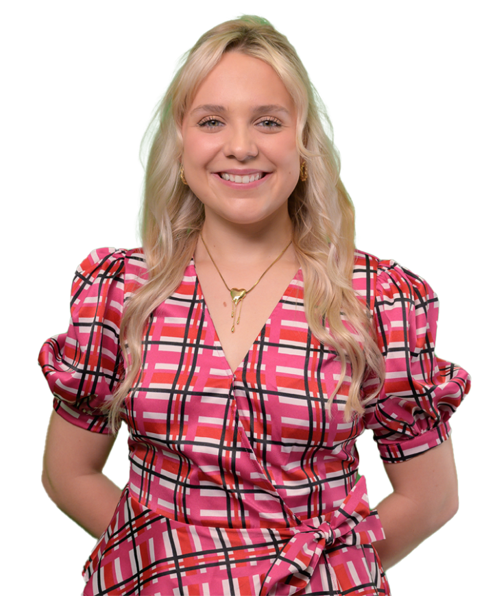 Katherine Whatley smiles with hands behind her back, she's wearing a pink plaid dress