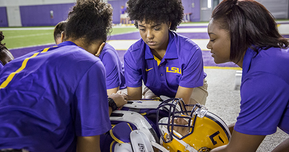 Students in an athletic training class practicing immobilizing a football player.