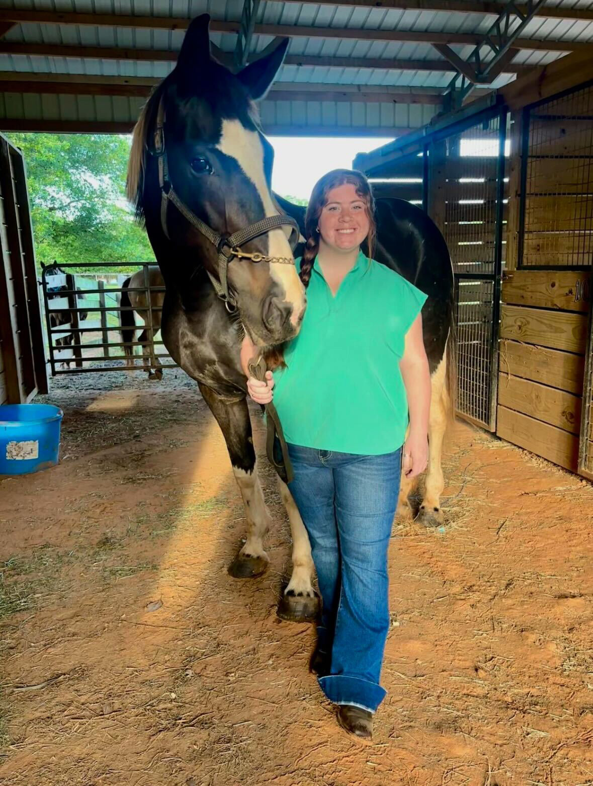 McCaelyn Beuschel, veterinary student, with a horse in a barn